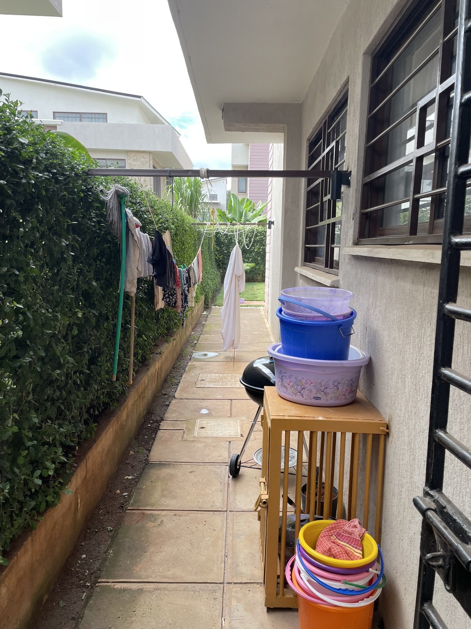 Covered exterior patio area with paving, garden bed, and perimeter wall near driveway blocks.